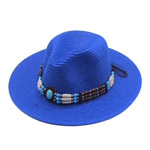 Dettaglio del nastro per cappello con perline turchesi su cappello da cowboy in paglia blu, primo piano.
