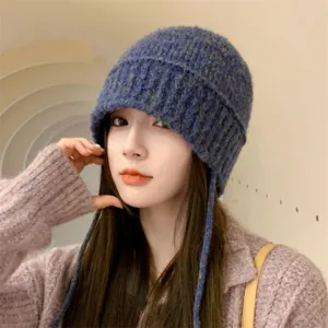 Primo piano dettagliato del cappello a secchiello in maglia blu con lacci, consistenza morbida.