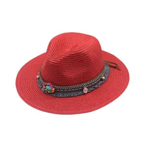 Vista detallada del sombrero fedora de paja roja con banda boho tejida, cuentas y flecos.
