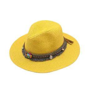 Detalle de la banda de cuentas coloridas y el dije turquesa en el sombrero de paja amarillo.