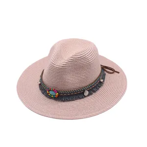Vista detallada de un sombrero fedora rosa de paja con banda de cuentas de colores.