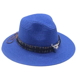 Blue straw hat detail featuring ethnic woven band and vintage metal bull skull ornament.