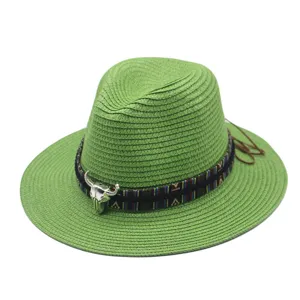 Detailed view of the green straw fedora hat featuring an ethnic band and silver bull skull decor.