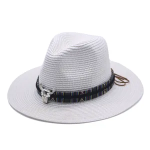 Detailed view of the white straw fedora hat with ethnic band and metal bull skull decor for summer beach.
