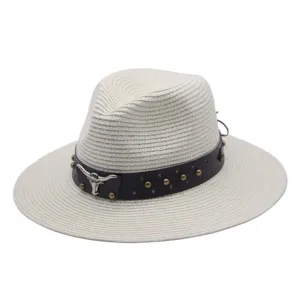 Detail view of white straw fedora hat featuring brown leather band with metal studs and bull skull.