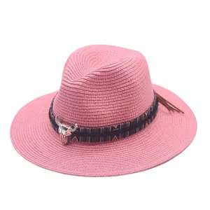 Pink straw fedora hat with ethnic band and metal bull skull decoration, ideal for summer.