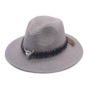 Detail view of a gray straw fedora hat with ethnic woven band and silver bull skull charm.