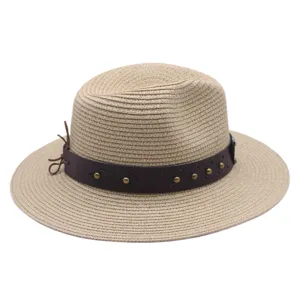 Detailed view of a stylish beige straw hat with a brown studded leather band for summer outdoor.