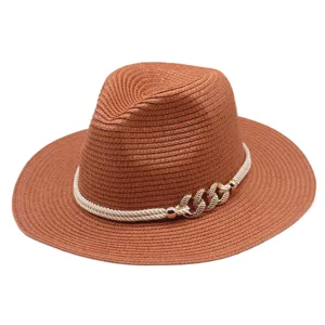Détail de chapeau fedora en paille marron pour femme, avec corde et chaîne dorée.