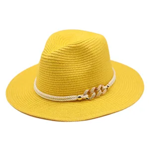 Détail rapproché du chapeau de paille jaune avec corde blanche et chaîne dorée élégante.