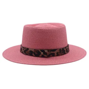 Detailopname van de roze zomerse strohoed met chique luipaardprint band en metalen knop.