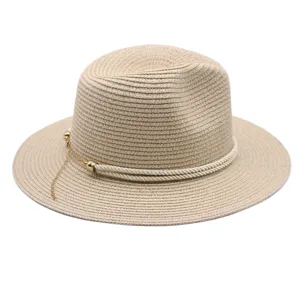 Gros plan détaillé d'un élégant chapeau de paille beige avec corde blanche et chaîne dorée.