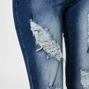 Close-up detail of women's stretch ripped denim jeans featuring stylish distressed frayed holes.