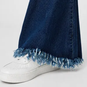 Detailed close-up of women's stretch denim jeans featuring a trendy frayed cuff hem design.
