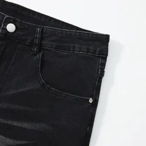Primo piano dei dettagli di jeans in denim nero da uomo con tasca e cintura visibile.