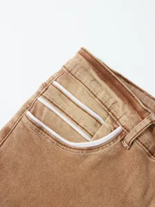 Primo piano dei dettagli di jeans da uomo marroni rétro con tasche rifinite in bianco.