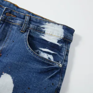 Vista di dettaglio di pantaloncini in denim elasticizzato lavato da uomo con effetto schizzato.