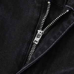 Primo piano della cerniera dei jeans neri lavati, dettagli in metallo di qualità e cuciture.