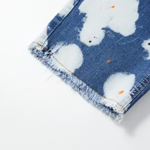 Dettaglio pantaloncini di jeans da uomo con motivo a spruzzi e orlo sfrangiato chic.