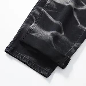 Dettaglio di jeans da uomo in denim lavato con risvolto e texture nera in stile vintage.