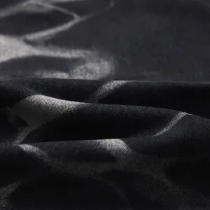 Primo piano del tessuto in denim lavato con effetto tie-dye e trama dettagliata.