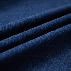 Detailed close-up of dark blue denim fabric with visible twill weave and soft drapes texture.