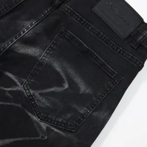 Primo piano dettagliato della tasca posteriore e della toppa in pelle di jeans neri.