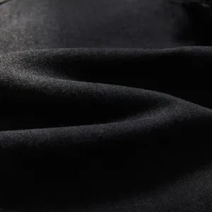 Gros plan sur le détail du tissu denim stretch noir montrant une texture sergée fine et lavage