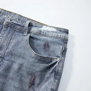 Dettaglio tasca pantaloncini jeans uomo, tessuto lavato chiaro con spruzzi di vernice.