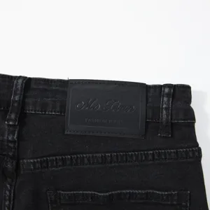 Vista dettagliata di jeans da uomo in denim nero slavato con etichetta in pelle sul retro.