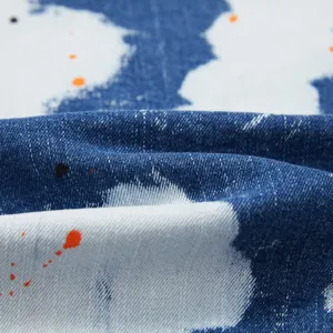 Primo piano dettagliato di tessuto denim lavato elasticizzato con motivo a spruzzi.