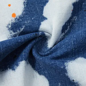 Primo piano dettagliato del tessuto jeans elasticizzato blu con macchie di vernice.