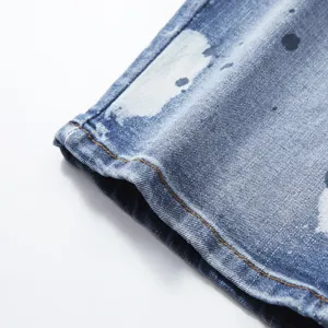 Men's summer stretch denim shorts detailed view with trendy paint splatter pattern and orange stitching.