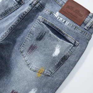 Dettaglio tasca posteriore pantaloncini denim uomo, lavaggio blu con schizzi di vernice.