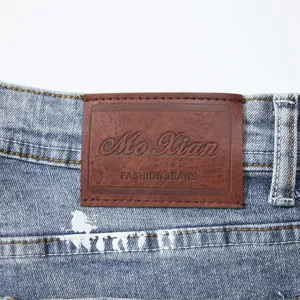 Primo piano di pantaloncini in denim da uomo con elegante patch in pelle e schizzi.