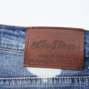 Detail shot of men's denim shorts with leather brand patch and splatter paint pattern texture.