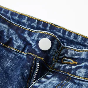 Gros plan détaillé de jeans en denim délavé vintage, coutures contrastées et quincaillerie.