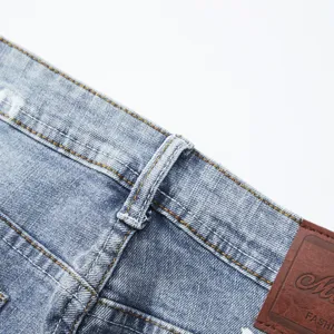 Dettaglio della cintura di pantaloncini di jeans da uomo con tessuto e patch in pelle.