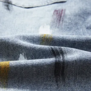 Primo piano dettagliato del tessuto di pantaloncini in denim elastico con schizzi di colore.