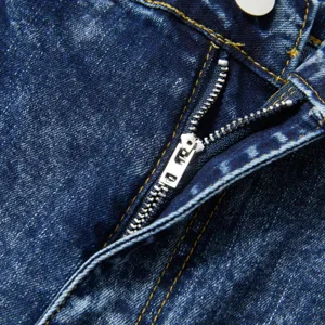Gros plan détaillé sur la braguette zippée et les coutures jaunes du jean vintage homme.
