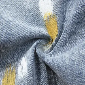 Primo piano dettagliato di tessuto denim elasticizzato blu con particolare stampa a spruzzi.
