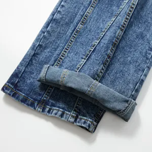 Gros plan détail de jeans droits vintage délavés pour homme avec revers et coutures jaunes.