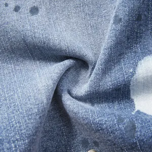 Close-up detail of blue stretch denim fabric with stylish splash ink pattern print texture.