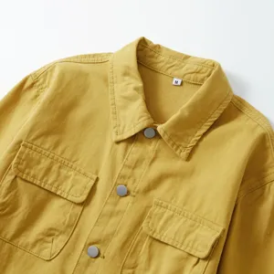 Primer plano detallado de la camisa de trabajo de algodón amarillo con bolsillo y botón.