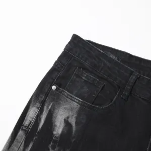 Detailed view of men's black washed denim jeans featuring unique splash ink tie dye design.