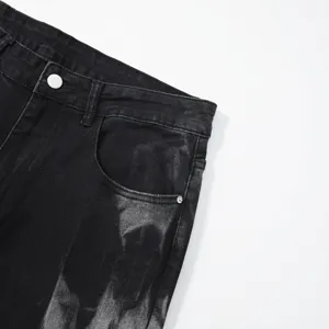 Close-up detail shot of men's black acid wash denim jeans waistband and front pocket.
