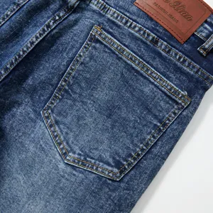 Détail de jean denim délavé rétro pour homme, coupe droite, ton bleu, couture poche arrière.