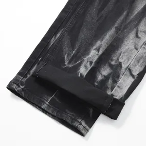 Close-up detail of mens black washed denim jeans featuring cuffed hem and textured fabric.