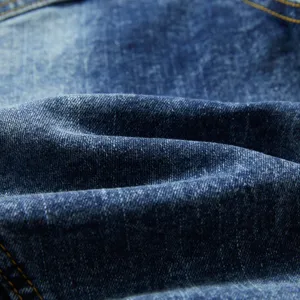 Gros plan sur la texture du tissu en denim lavé avec un matériau en coton bleu et des coutures.