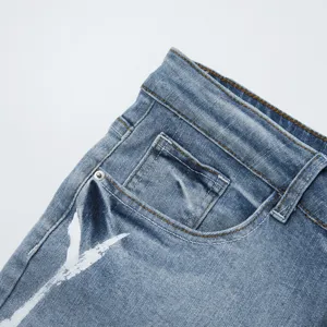 Dettaglio pantaloncini di jeans elasticizzati uomo, design con schizzi di pittura.